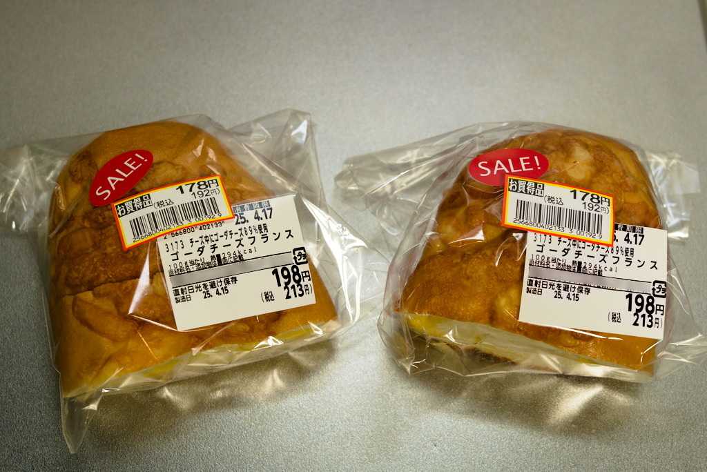 A pair of cheese bread buns with discount sticker on them