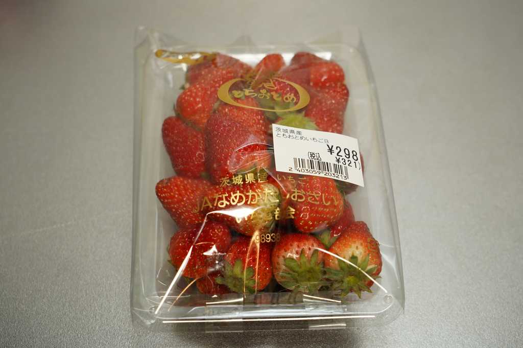 A pack of strawberries, the fruit are of smaller size, some are still a bit greenish